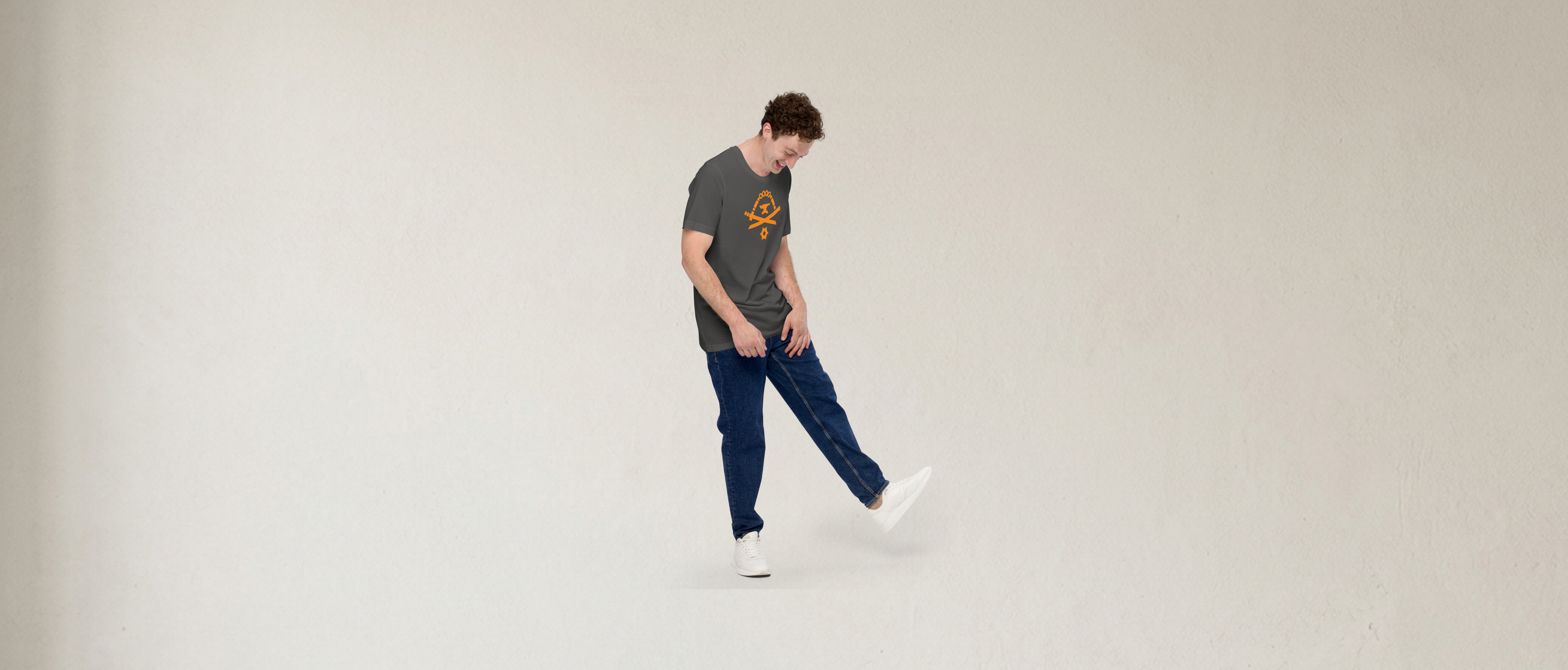 Fashionable male model laughing and wearing an asphalt-colored 100% airlume cotton t-shirt featuring classic fan-made orange golden weapons ninja blacksmith shop logo design. Item is a BRKDrip AFOL essentials shirt with a modern elemental brick master aesthetic.