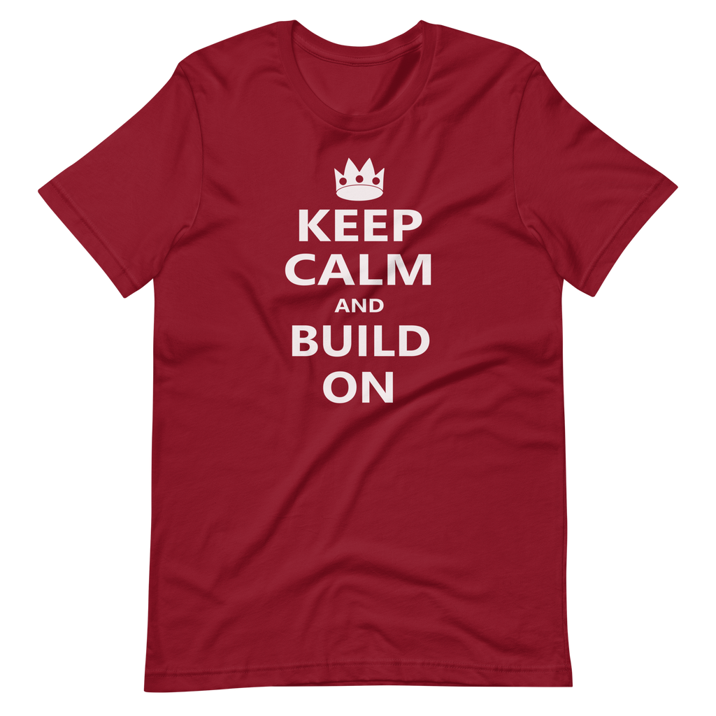 Wrinkled cardinal red 100% airlume cotton t-shirt featuring OG castle crown and parody AFOL saying: "Keep Calm and Build On". Item is a BRKDrip AFOL essentials shirt with a modern brick-inspired aesthetic.