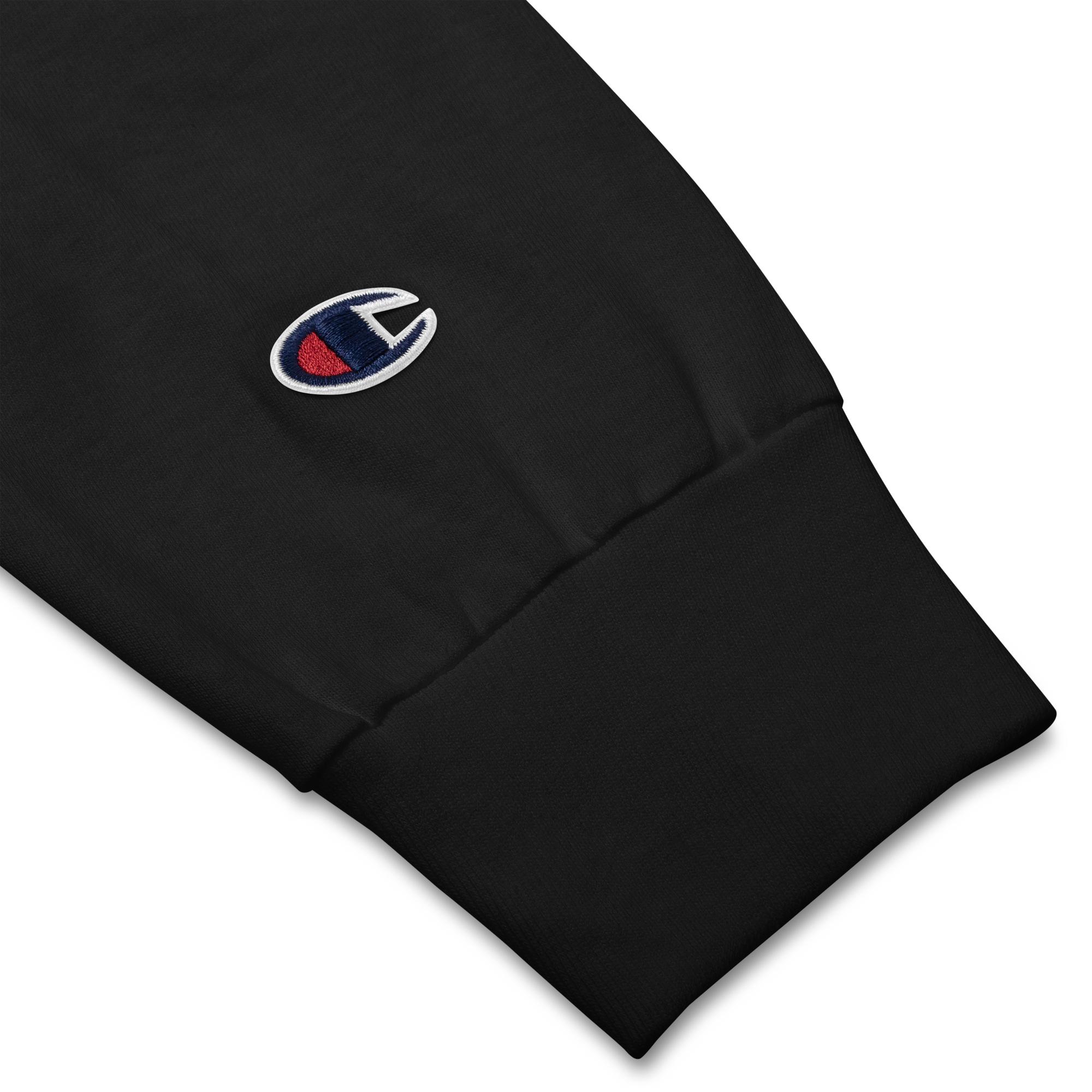 Close-up of Champion© emblem stitching on sleeve of black lightweight, 100% cotton luxury Champion© shirt featuring space shuttle emblem embroidered in the top right corner. Item is a BRKDrip Builder's Collection luxury longsleeve shirt with a classic town building block aesthetic.