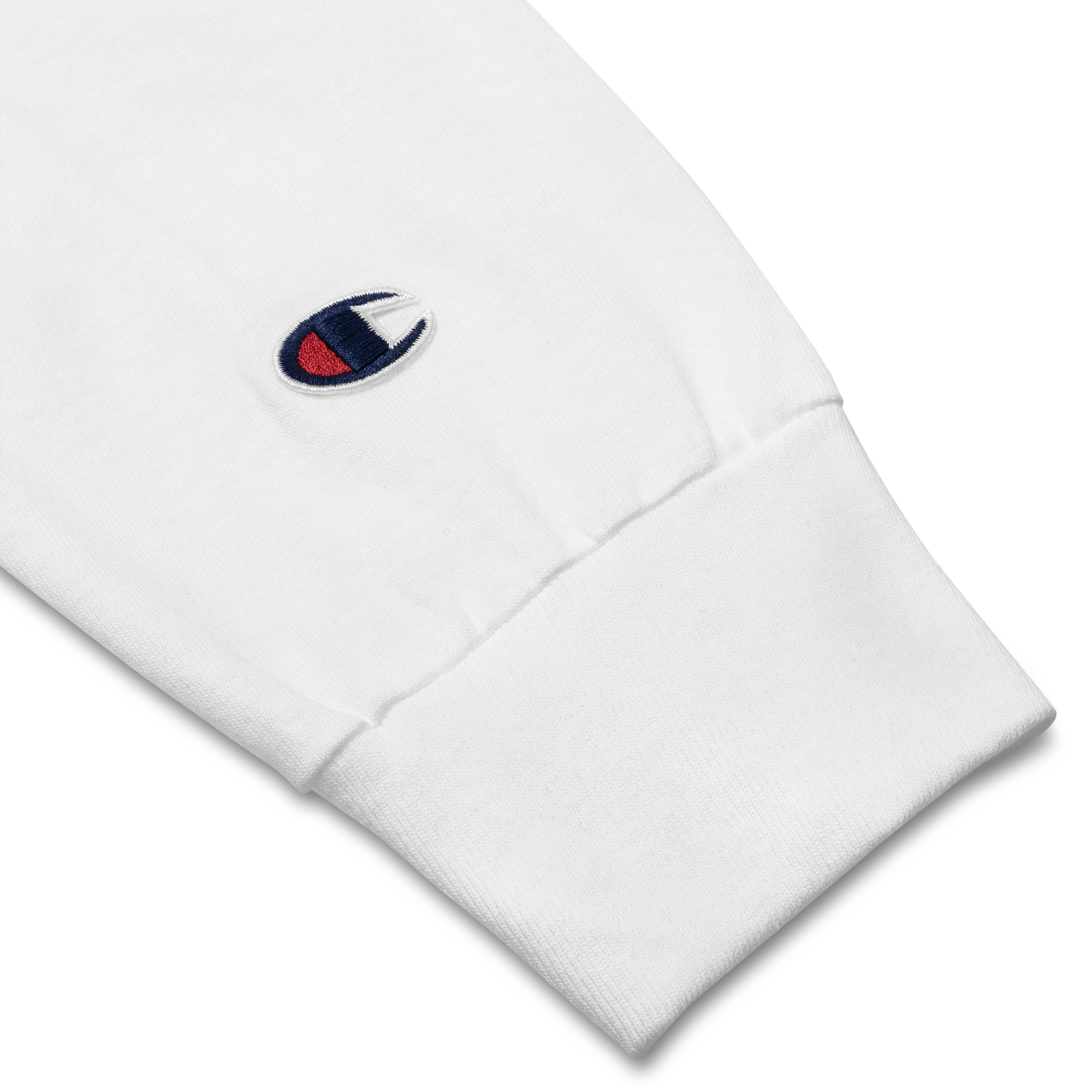 Close-up of Champion© emblem stitching on sleeve of white lightweight, 100% cotton luxury Champion© shirt featuring space shuttle emblem embroidered in the top right corner. Item is a BRKDrip Builder's Collection luxury longsleeve shirt with a classic town building block aesthetic.