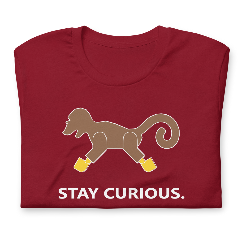 Folded cardinal red 100% airlume cotton t-shirt featuring classic fan-made brick monkey design with parody AFOL slogan "Stay Curious". Item is a BRKDrip AFOL essentials shirt with a vintage pirate building blocks aesthetic.
